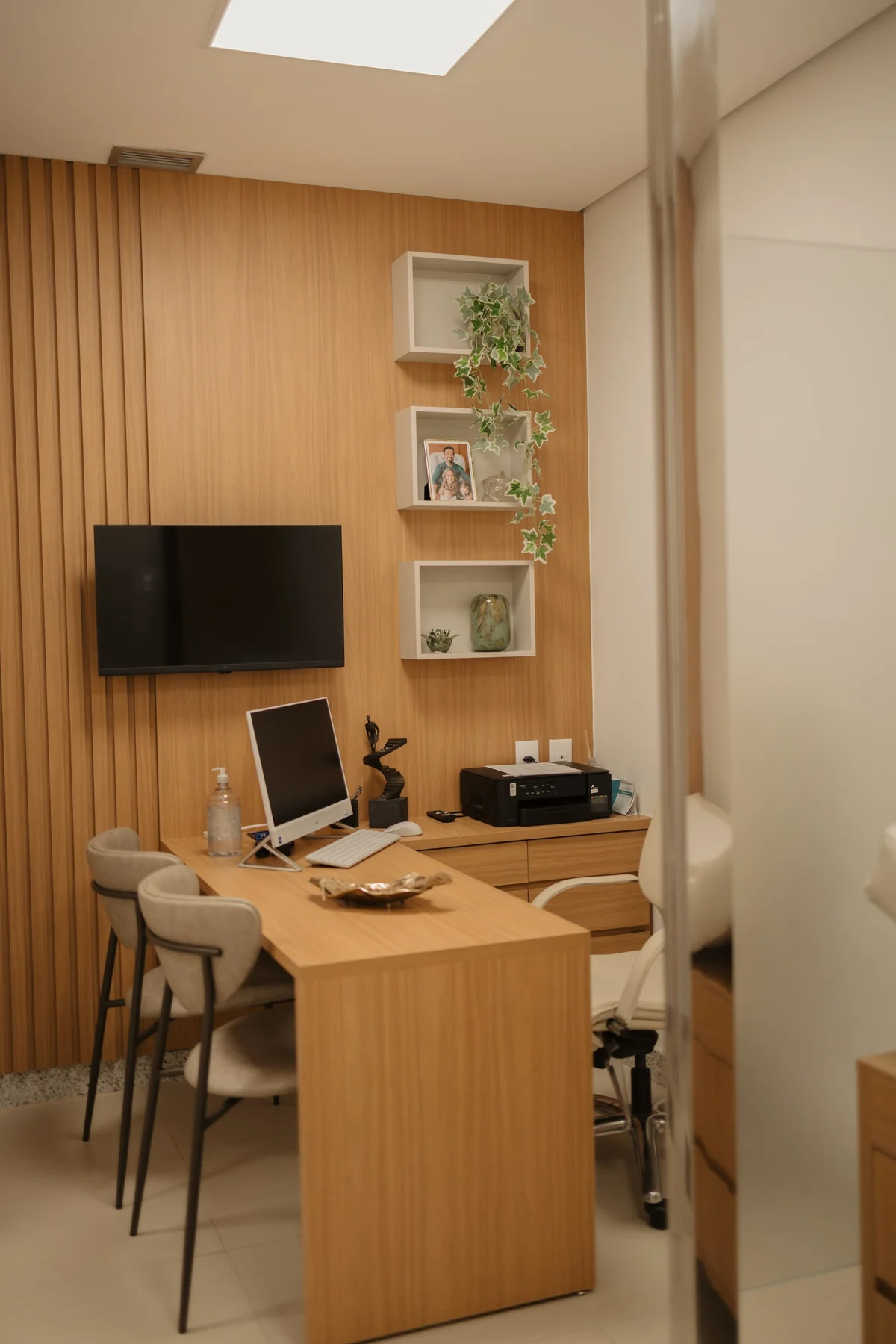 Mesa de atendimento do consultório, com painel ripado de madeira ao fundo